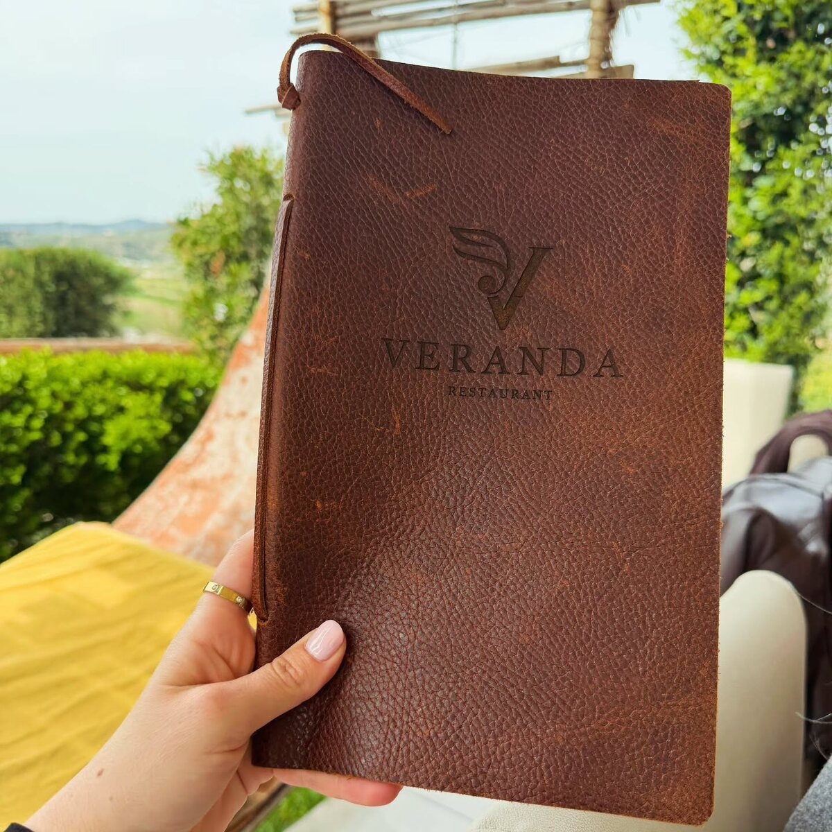 Brown textured leather menu cover with an embossed restaurant logo